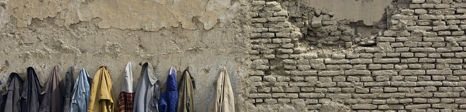 Afghan students' coats hanged on the wall destroyed by the war, Kabul, Afghanistan 